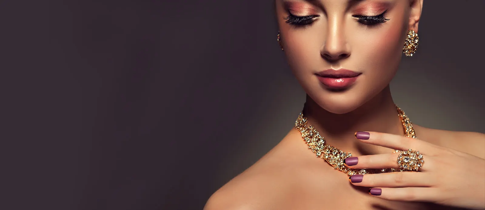 A model wearing a gold and diamond necklace, earrings and cocktail ring